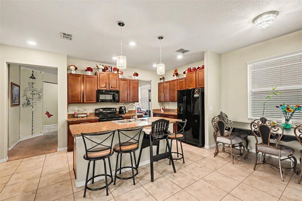 A kitchen features wood cabinets, granite countertops, a breakfast bar, and a dining area — 11334 VILLAS ON THE GREEN DR, RIVERVIEW, FL