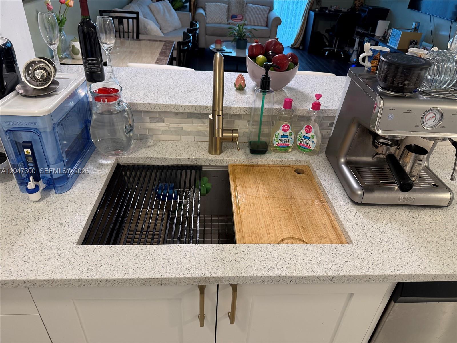 A kitchen with white cabinets and a breakfast bar overlooks a living area with dark flooring — 1745 E Hallandale Beach Blvd # 304W, Hallandale Beach FL 33009, HALLANDALE BEACH, FL