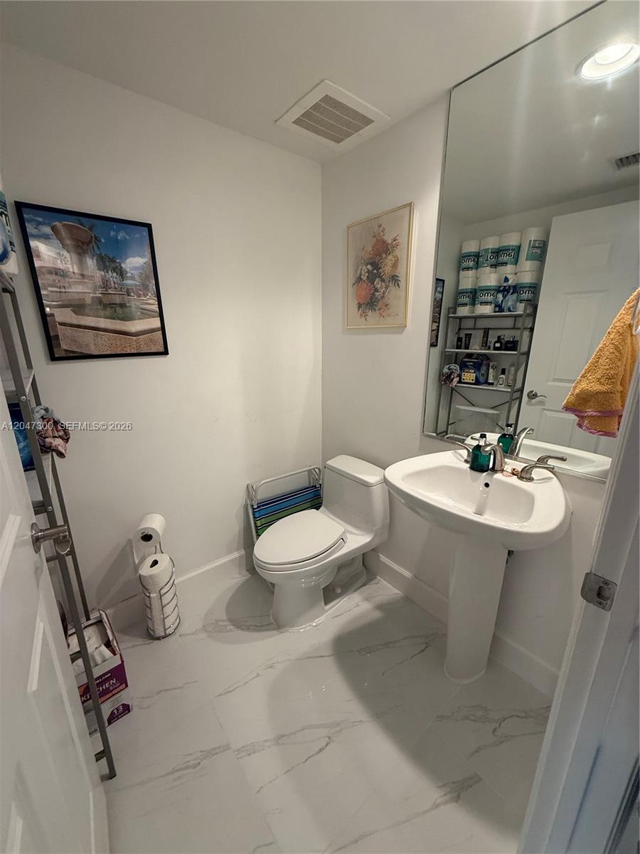 An empty room features sage green walls, dark wood-look flooring, and a sliding glass balcony door — 1745 E Hallandale Beach Blvd # 304W, Hallandale Beach FL 33009, HALLANDALE BEACH, FL