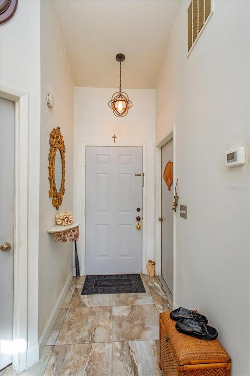 An entryway features a light-colored door, a hanging pendant light, and tiled flooring — 2501 LONG MEADOW WAY, ORLANDO, FL
