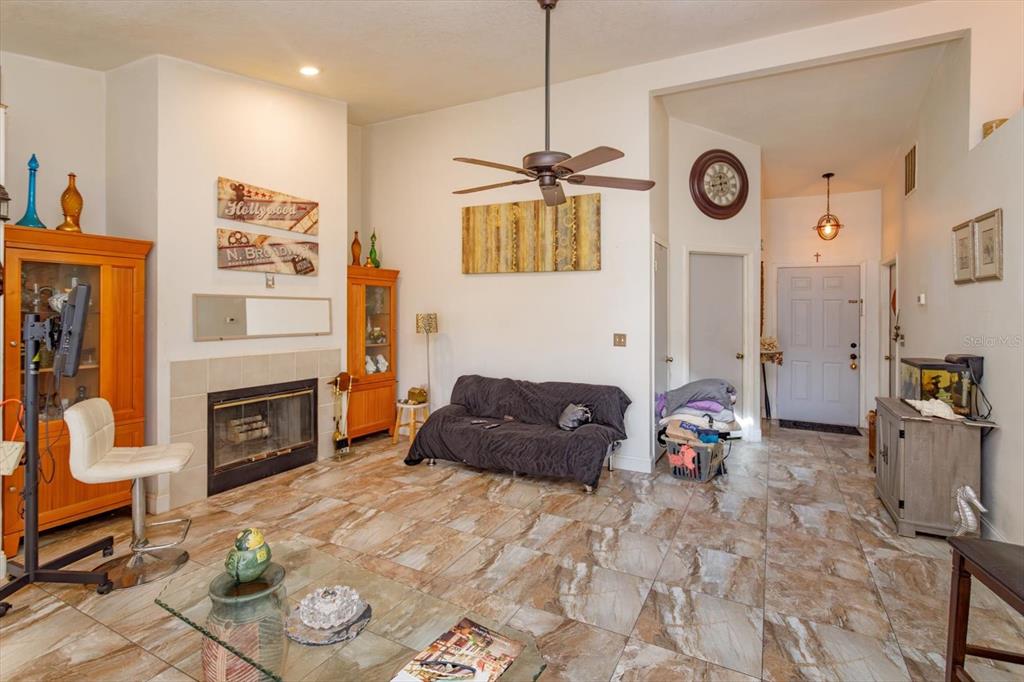 A living room features a fireplace, tile flooring, a ceiling fan, and a front door — 2501 LONG MEADOW WAY, ORLANDO, FL