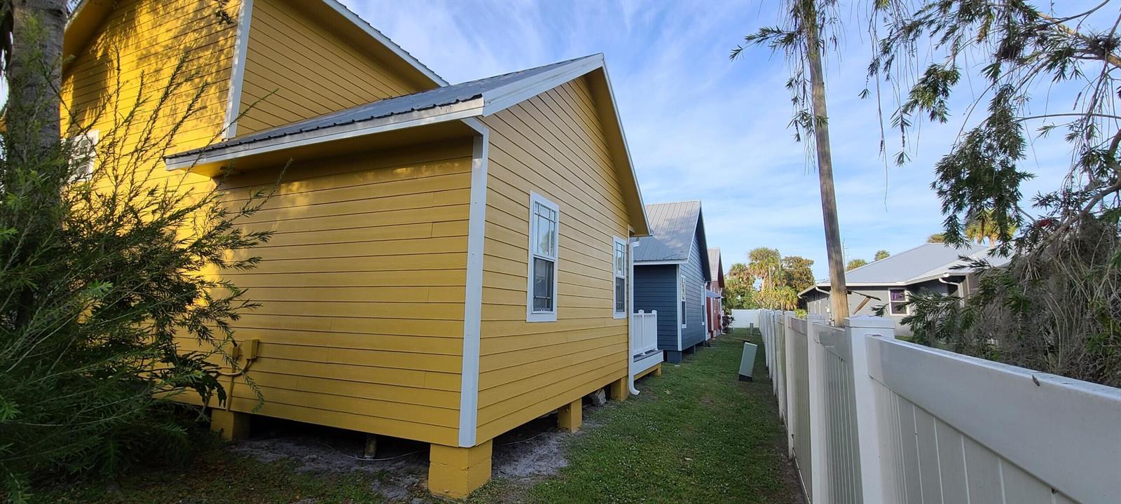 A yellow house with horizontal siding stands next to a white fence and neighboring homes — 4334 SE Us Highway 441 # 11, Okeechobee FL 34974, OKEECHOBEE, FL