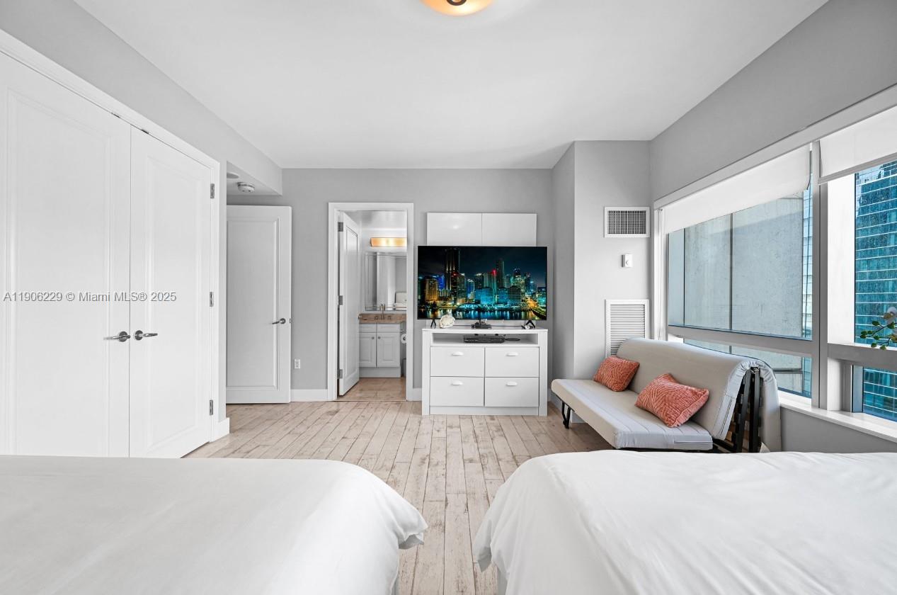 A bedroom features two beds, a sofa, a television, and large windows with city views — 1435 Brickell Ave # 3401, Miami FL 33131, MIAMI, FL