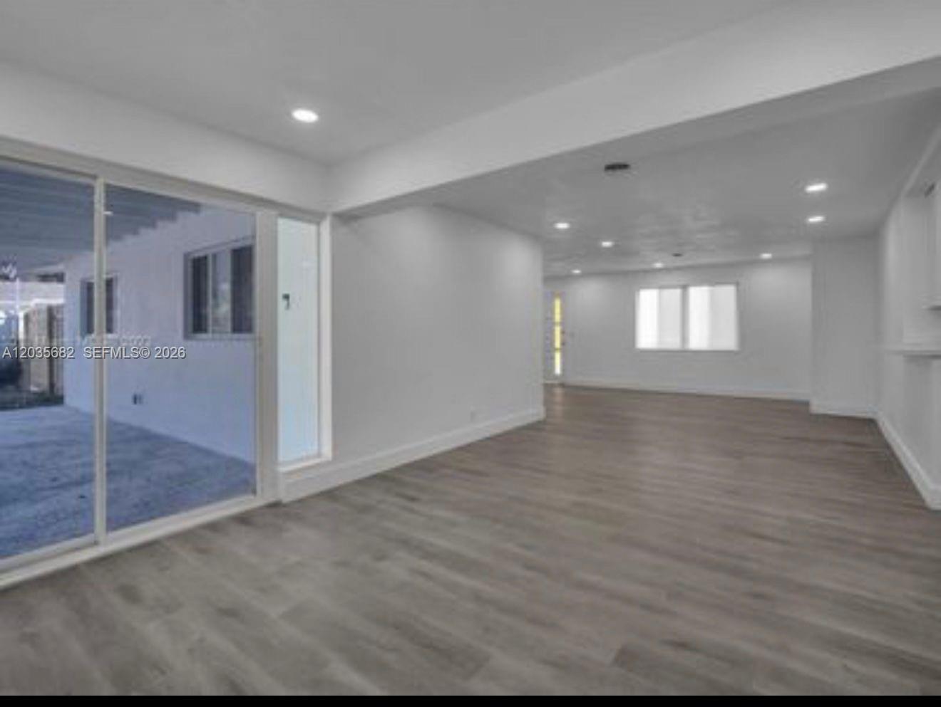 An interior view of a bright, open-concept living area with white walls and gray flooring — 3811 NW 6th Pl # 0, Lauderhill FL 33311, LAUDERHILL, FL