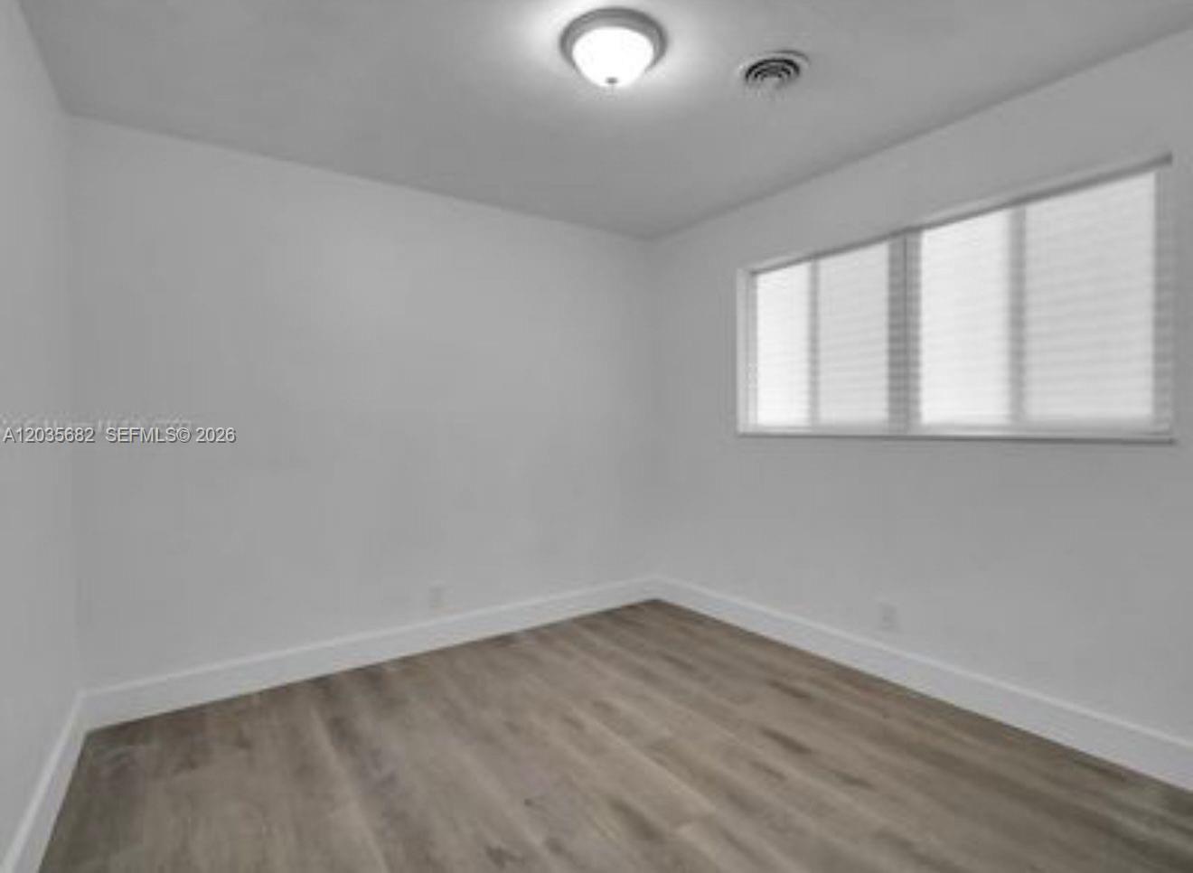 An empty room features white walls, light wood-look flooring, a ceiling light, and a window — 3811 NW 6th Pl # 0, Lauderhill FL 33311, LAUDERHILL, FL