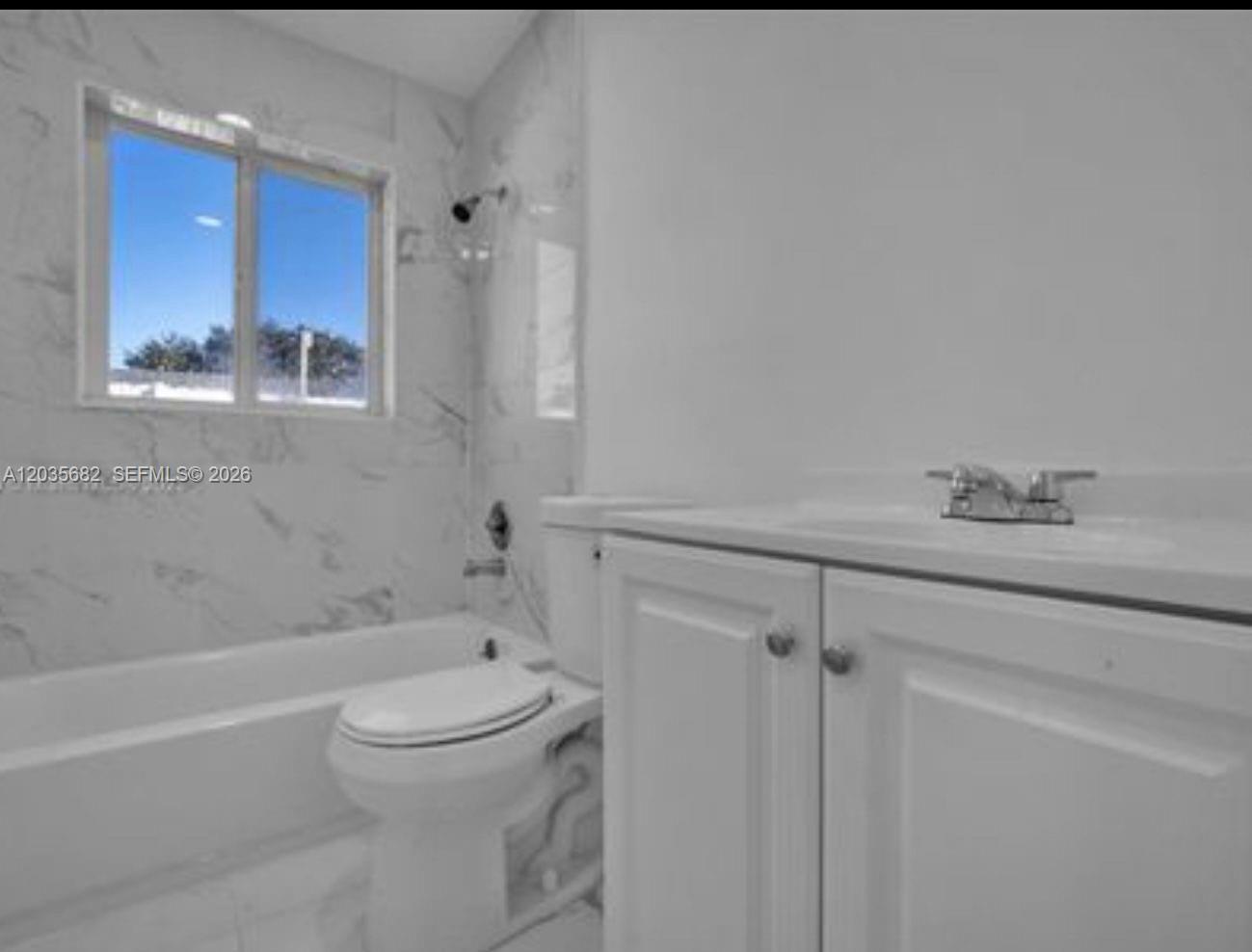 A bathroom features a white vanity, a toilet, and a bathtub with marble-look tile walls — 3811 NW 6th Pl # 0, Lauderhill FL 33311, LAUDERHILL, FL