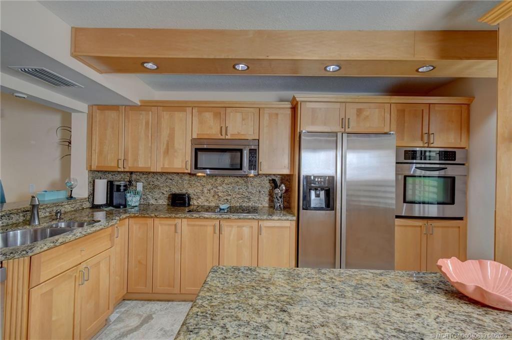 A kitchen features light wood cabinets, stainless steel appliances, and speckled granite countertops — 10980 S Ocean Drive # 114, Jensen Beach FL 34957, JENSEN BEACH, FL