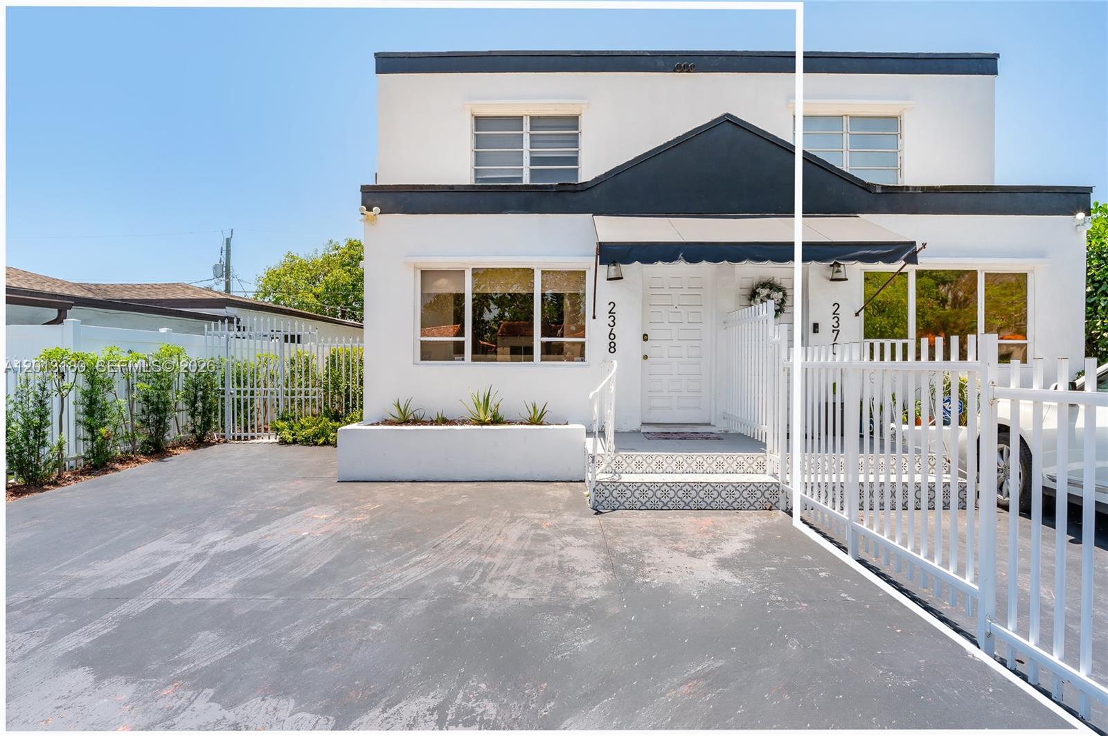 A two-story white duplex with a black awning and a paved driveway behind a fence — 2368 SW 26th St # A, Miami FL 33133, MIAMI, FL