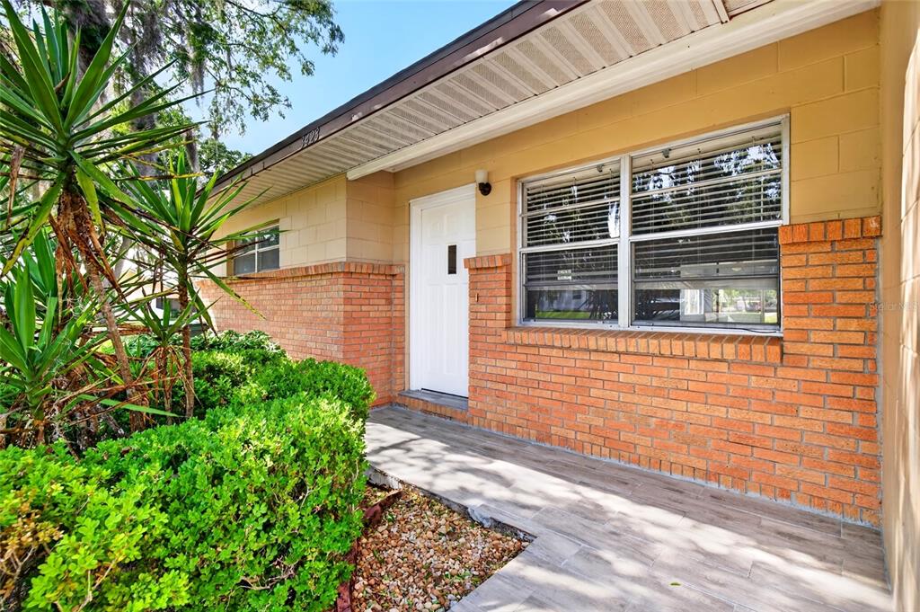 A brick and block house exterior features a white front door and a tiled porch — 3423 SW 27TH STREET, OCALA, FL