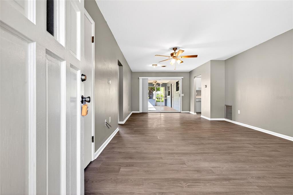 A living room with wood-look flooring, a ceiling fan, and a sliding glass door — 3423 SW 27TH STREET, OCALA, FL