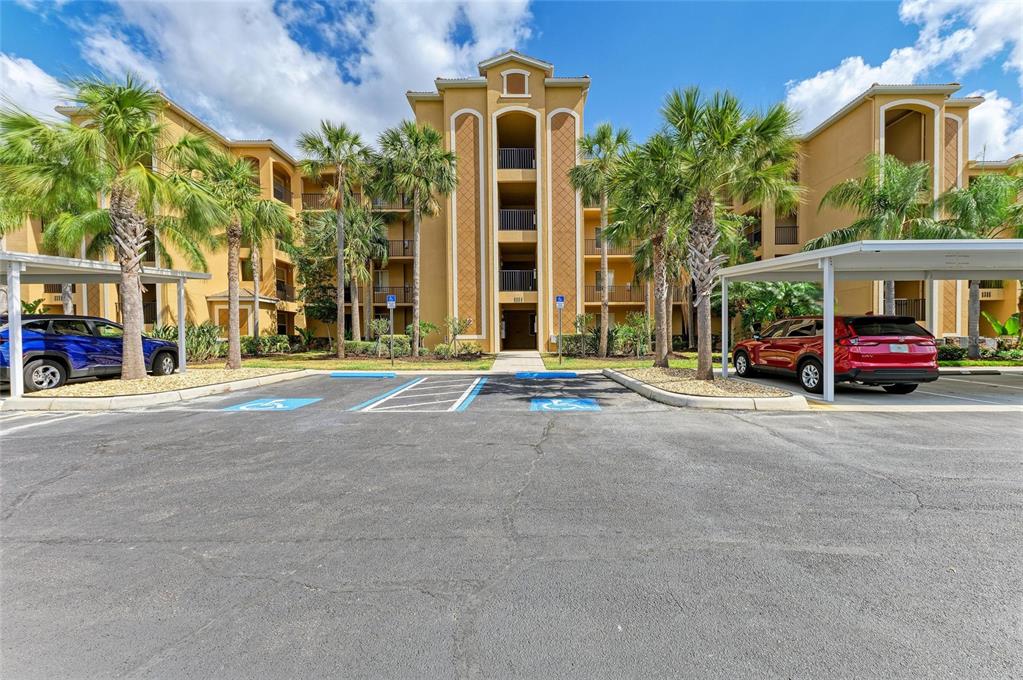 A multi-story apartment building with a parking lot and two covered carports in front — 8309 GRAND ESTUARY TRAIL UNIT 205, BRADENTON, FL