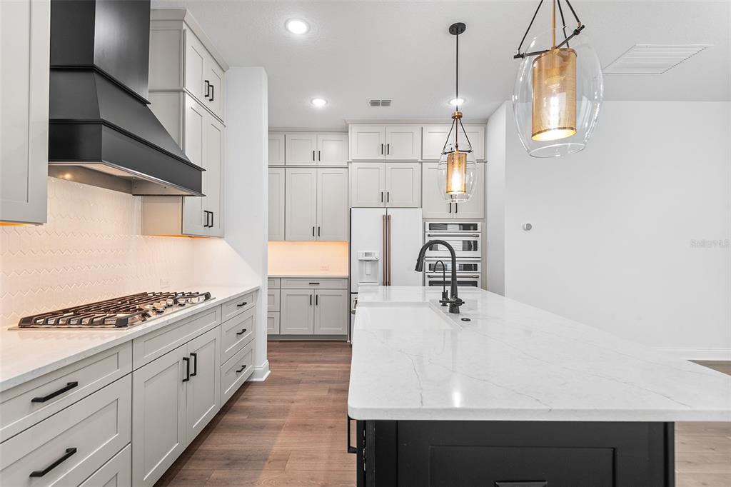 A modern kitchen features light gray cabinetry, a black range hood, and a white island — 1619 S OSCEOLA AVENUE, ORLANDO, FL
