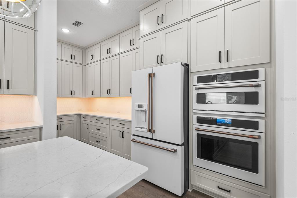 A modern kitchen features light gray cabinetry, white countertops, a white refrigerator, and double ovens — 1619 S OSCEOLA AVENUE, ORLANDO, FL