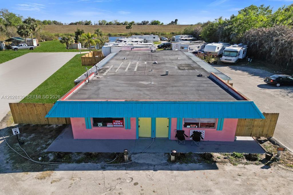 An aerial view shows a pink and blue building with a flat roof and parking — 1421 NE US Highway 441 # 10, Okeechobee FL 34974, OKEECHOBEE, FL