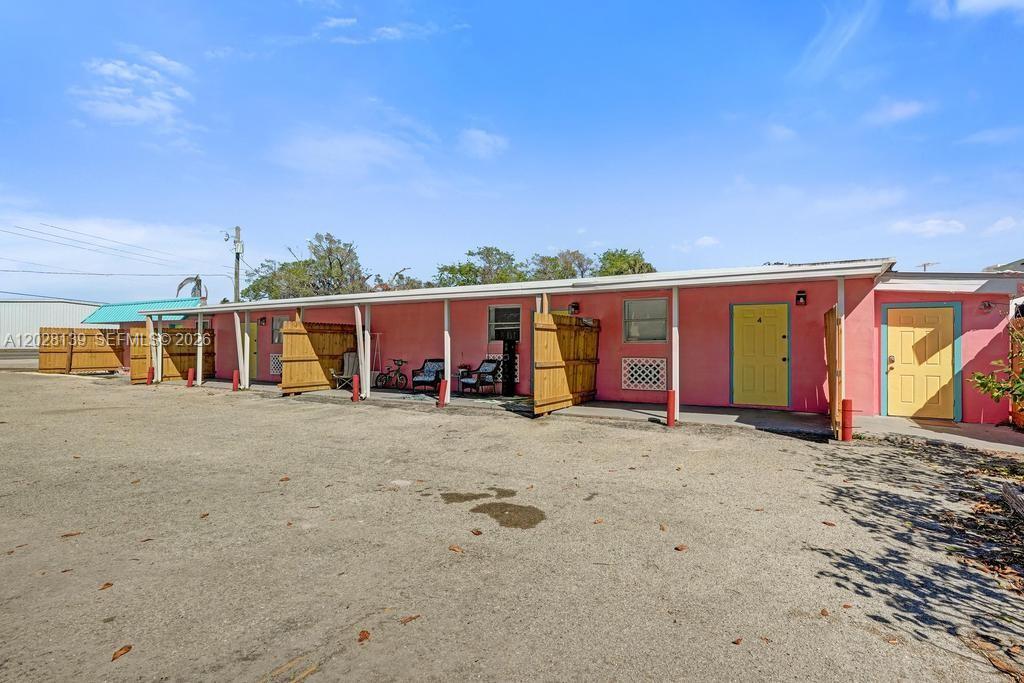 A pink, single-story motel-style building features several doors and wooden privacy fences — 1421 NE US Highway 441 # 10, Okeechobee FL 34974, OKEECHOBEE, FL