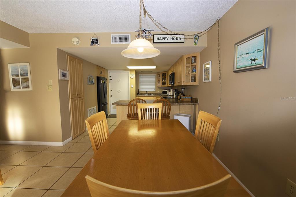 A dining area with a wooden table and chairs sits adjacent to a kitchen — 1571 S ATLANTIC AVENUE UNIT 303, NEW SMYRNA BEACH, FL