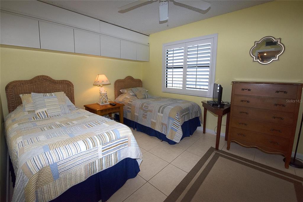 A bedroom with two twin beds, wicker headboards, yellow walls, and a wooden dresser — 1571 S ATLANTIC AVENUE UNIT 303, NEW SMYRNA BEACH, FL