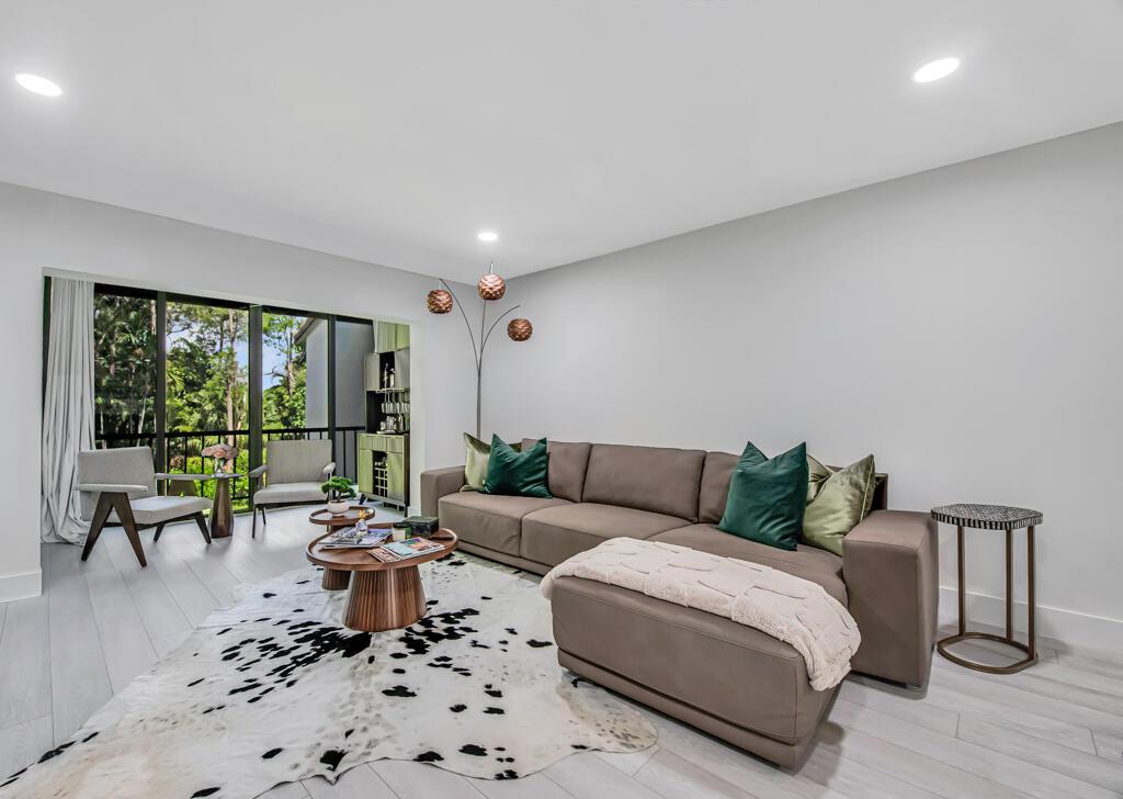 A living room features a brown sectional sofa, a cowhide rug, and a glass balcony door — 21362 Juego Circle # D, Boca Raton FL 33433, BOCA RATON, FL