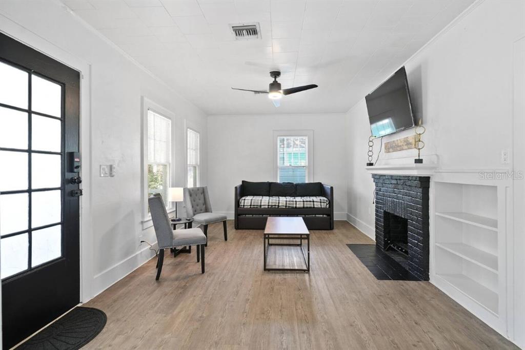 A living room features white walls, wood-look flooring, a black fireplace, and a ceiling fan — 1829 HOLLENBECK DRIVE, ORLANDO, FL