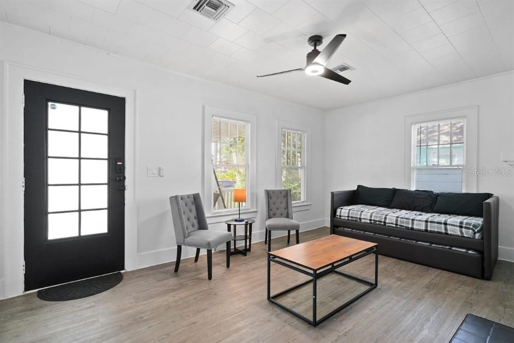 A living room features white walls, wood-look flooring, a black door, and a ceiling fan — 1829 HOLLENBECK DRIVE, ORLANDO, FL