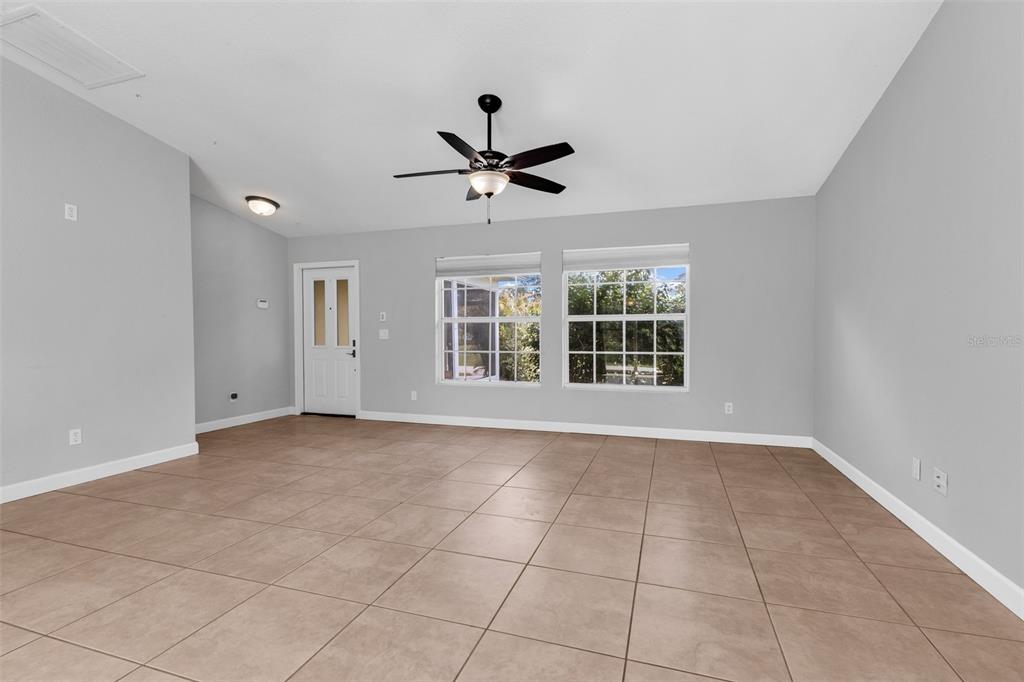 A spacious room with light gray walls, tiled flooring, a ceiling fan, and two windows — 1160 NUCELLI ROAD, NORTH PORT, FL