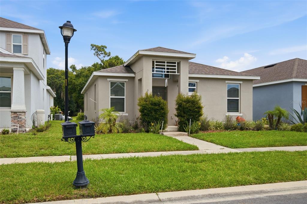 A single-story house with a tan stucco exterior, a front walkway, and a street lamp — 3121 ROCKY RIVER ROAD, KISSIMMEE, FL