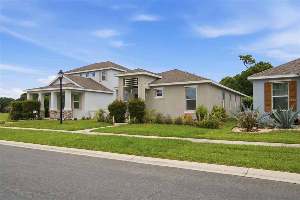 A two-story suburban house with a tan stucco exterior and a brown shingled roof — 3121 ROCKY RIVER ROAD, KISSIMMEE, FL