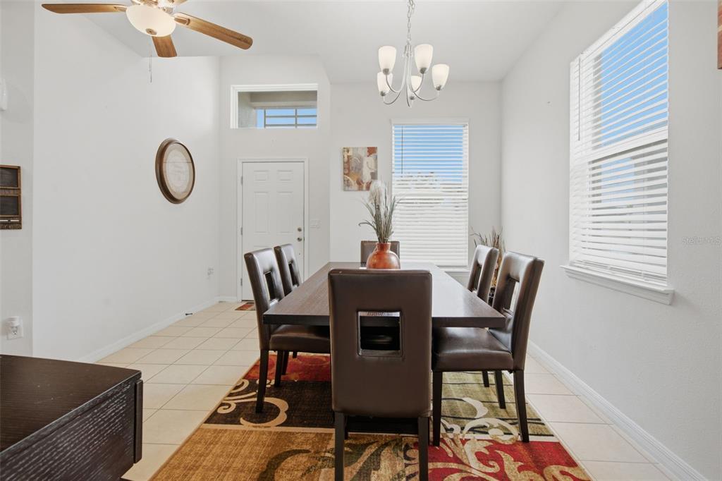 A dining room features a dark wood table, six chairs, and a patterned area rug — 3121 ROCKY RIVER ROAD, KISSIMMEE, FL