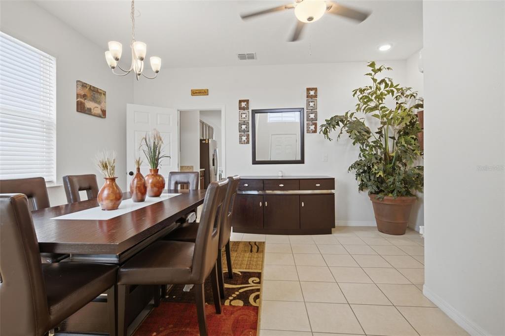 A dining room features a dark wood table, leather chairs, a sideboard, and a large plant — 3121 ROCKY RIVER ROAD, KISSIMMEE, FL
