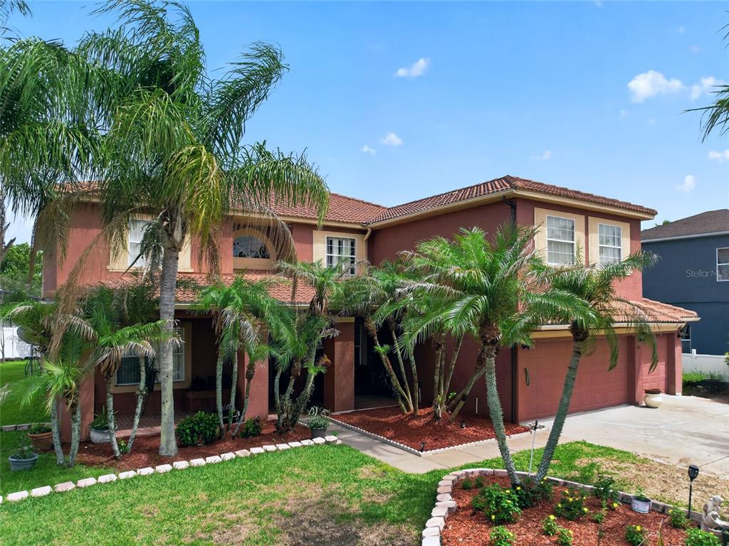 A two-story house with a terracotta roof, stucco exterior, and several palm trees in front — 202 WOODSON COURT, KISSIMMEE, FL