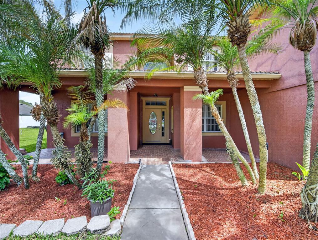 A two-story house with a tan front door and palm trees in the front yard — 202 WOODSON COURT, KISSIMMEE, FL