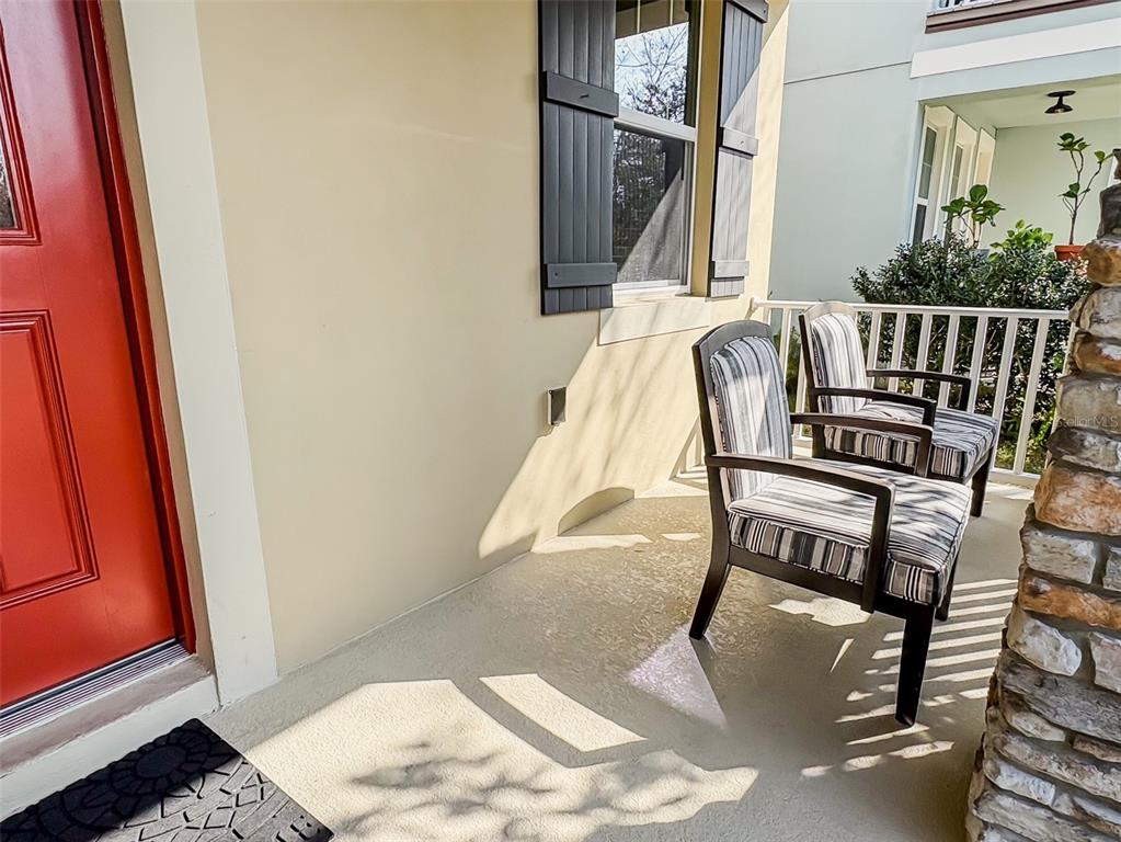 A covered porch features a red door, two striped chairs, and a stone pillar — 8607 RANDAL PARK BOULEVARD, ORLANDO, FL
