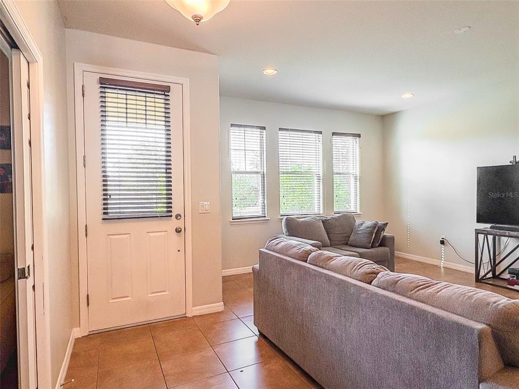 A living room with tile flooring, a front door, and a grey sofa set — 8607 RANDAL PARK BOULEVARD, ORLANDO, FL