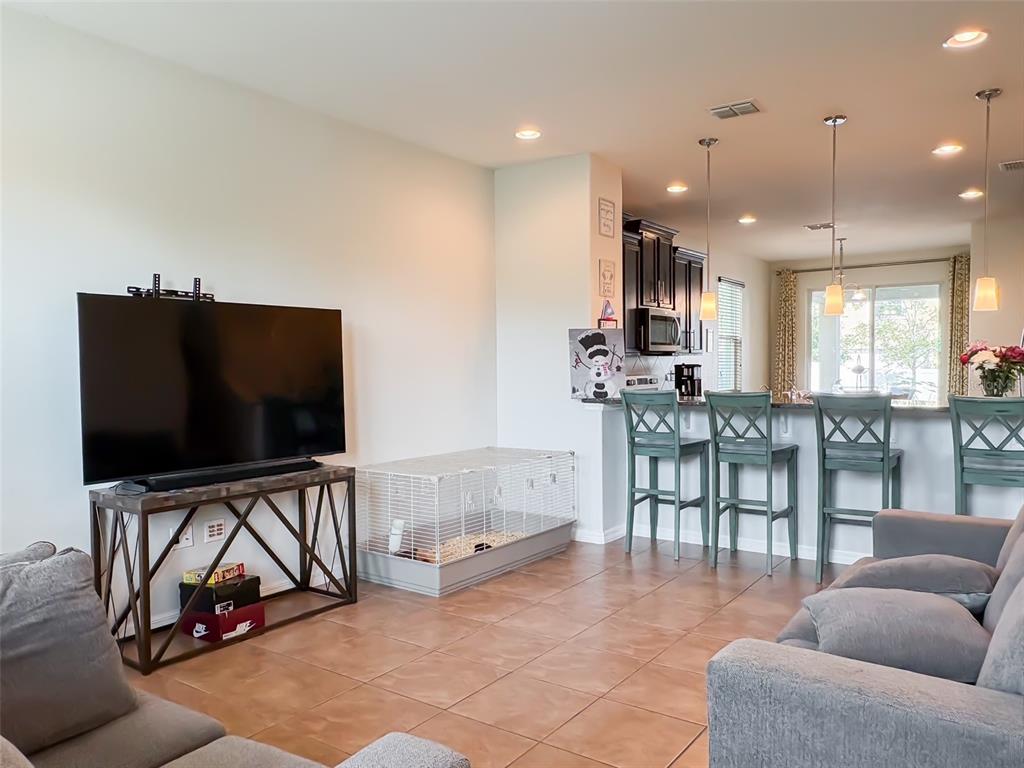 A living room with tile floors, a television on a stand, and an open kitchen — 8607 RANDAL PARK BOULEVARD, ORLANDO, FL