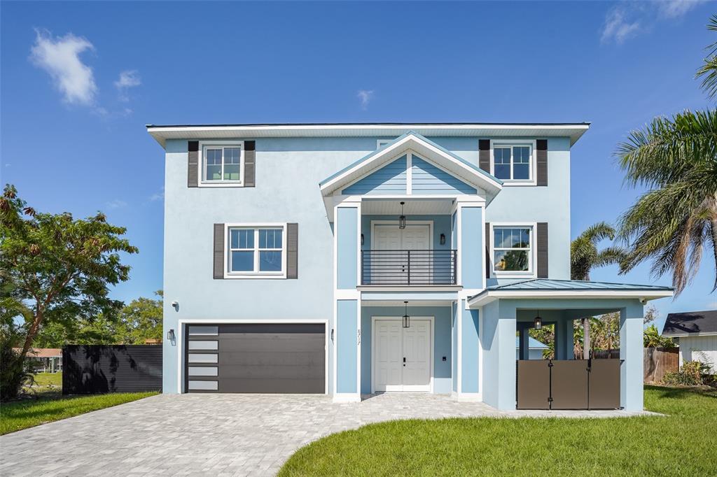 A light blue two-story house features a front balcony, a garage, and a paved driveway — 8717 DRIFTWOOD DRIVE, TAMPA, FL