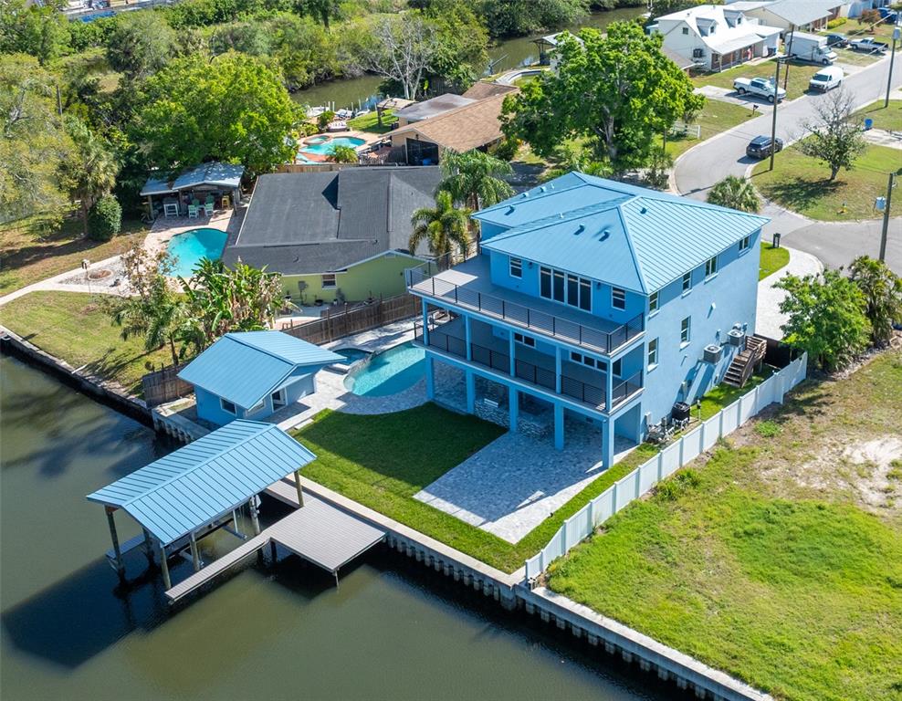 An aerial view of a blue multi-story waterfront house with a pool and boat dock — 8717 DRIFTWOOD DRIVE, TAMPA, FL