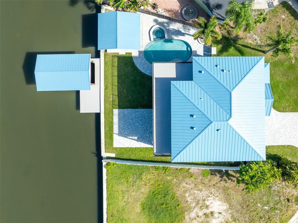 An aerial view shows a house with a blue metal roof, pool, and boat dock — 8717 DRIFTWOOD DRIVE, TAMPA, FL