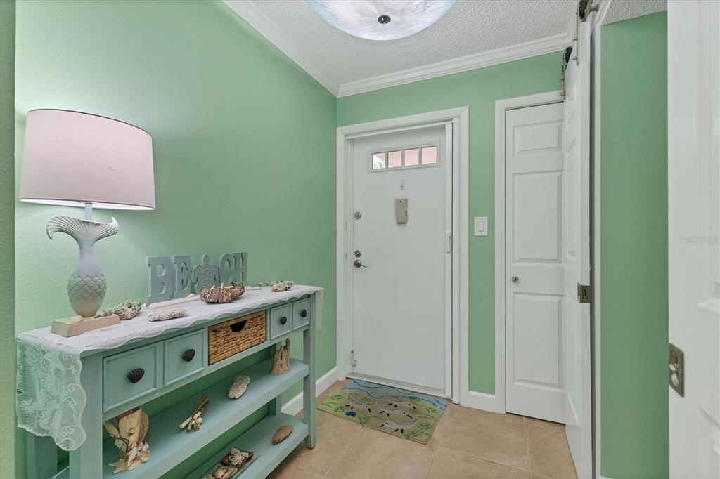 An entryway features mint green walls, a light blue console table, and a white door — 8776 MIDNIGHT PASS ROAD UNIT C107, SARASOTA, FL