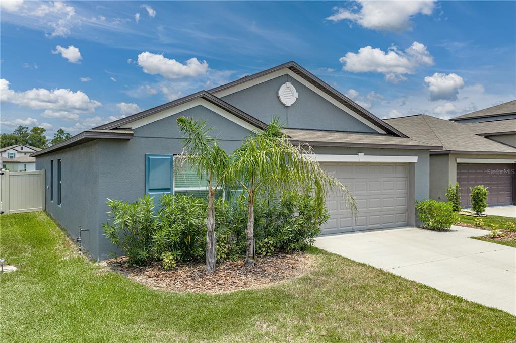 A gray single-story house features a two-car garage, a front lawn, and two palm trees — 4334 TROTTERS WAY, LAKELAND, FL