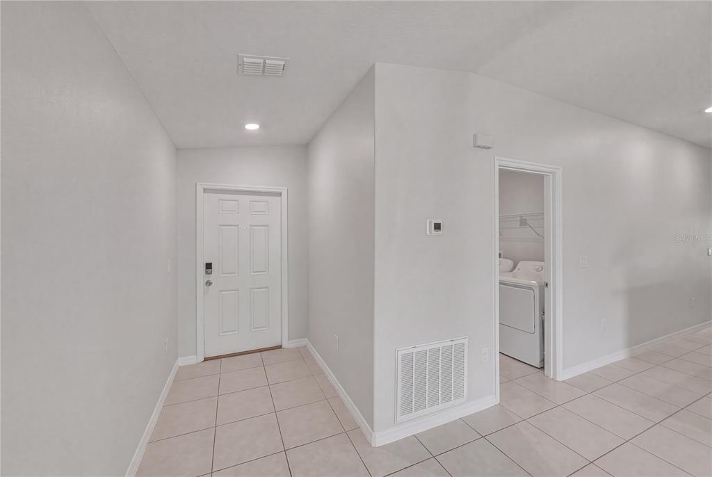 An entryway with tile flooring, a white front door, and a doorway to a laundry room — 4334 TROTTERS WAY, LAKELAND, FL