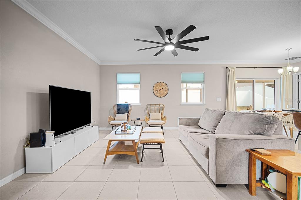 A living room features a grey sofa, a white media console, and two wicker chairs — 1328 WATER WILLOW DRIVE, GROVELAND, FL