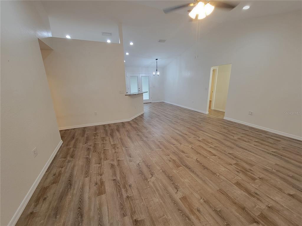 An open-concept living area features light-colored walls, vaulted ceilings, and wood-look laminate flooring — 8783 SE 157TH PLACE, SUMMERFIELD, FL