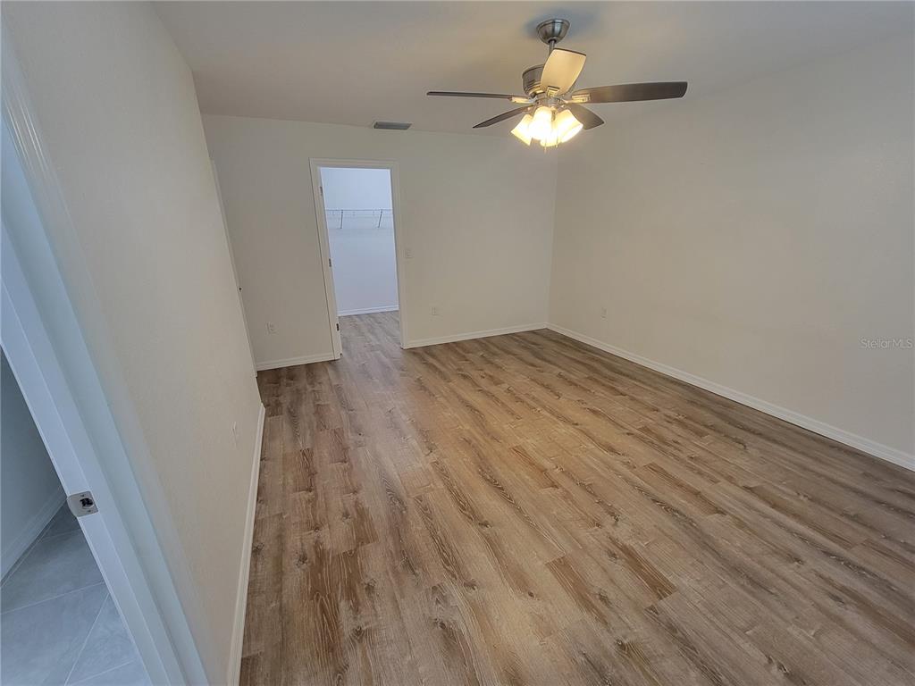 An empty bedroom features wood-look flooring, white walls, a ceiling fan, and an open closet — 8783 SE 157TH PLACE, SUMMERFIELD, FL
