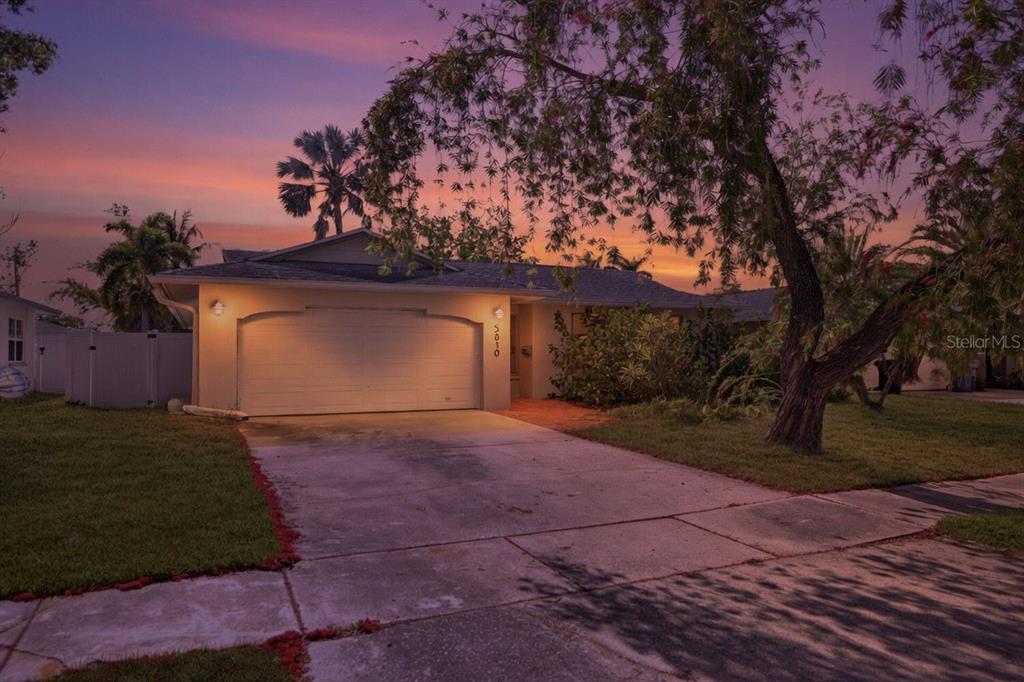 A single-story house with a garage and a concrete driveway at sunset — 5810 VENETIAN BOULEVARD NE, ST PETERSBURG, FL