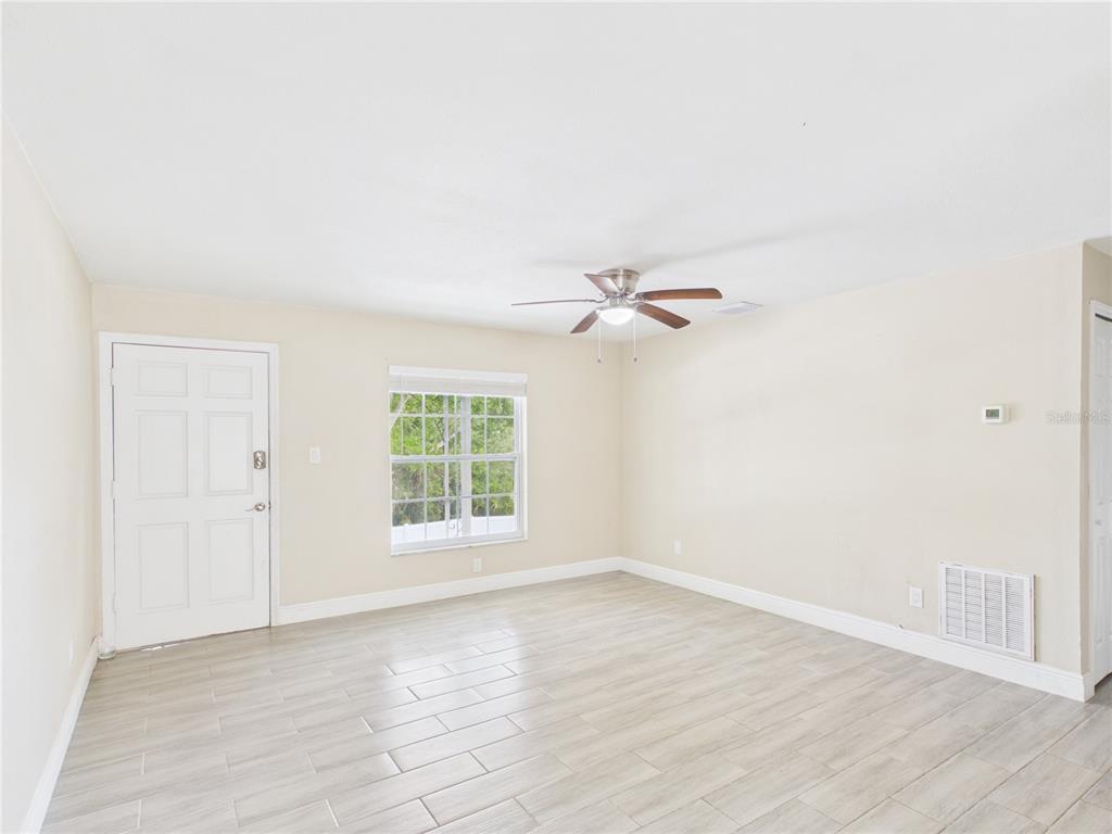 A living room with light-colored tile floors, beige walls, a ceiling fan, and a window — 2800 E 113TH AVENUE UNIT 219, TAMPA, FL
