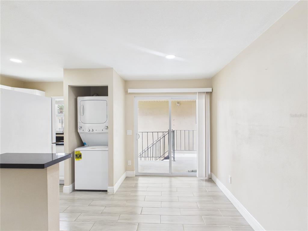 A dining area features light tile flooring, a stacked washer-dryer, and sliding glass balcony doors — 2800 E 113TH AVENUE UNIT 219, TAMPA, FL