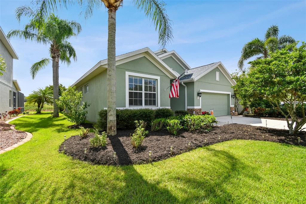 A green single-story house with a two-car garage, palm trees, and a landscaped front yard — 5056 LAKEHURST COURT, PALMETTO, FL