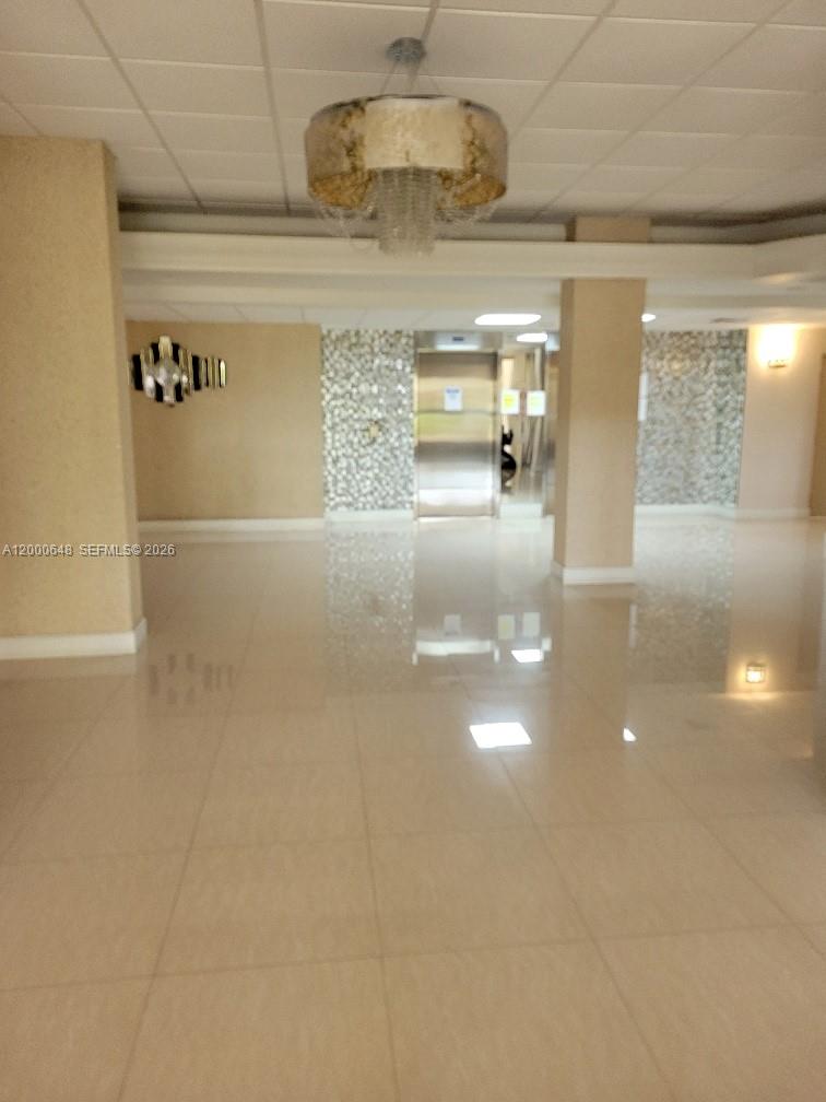 A lobby features a tiled floor, a crystal chandelier, and a metallic elevator door — 1833 S Ocean Dr # 307, Hallandale Beach FL 33009, HALLANDALE BEACH, FL