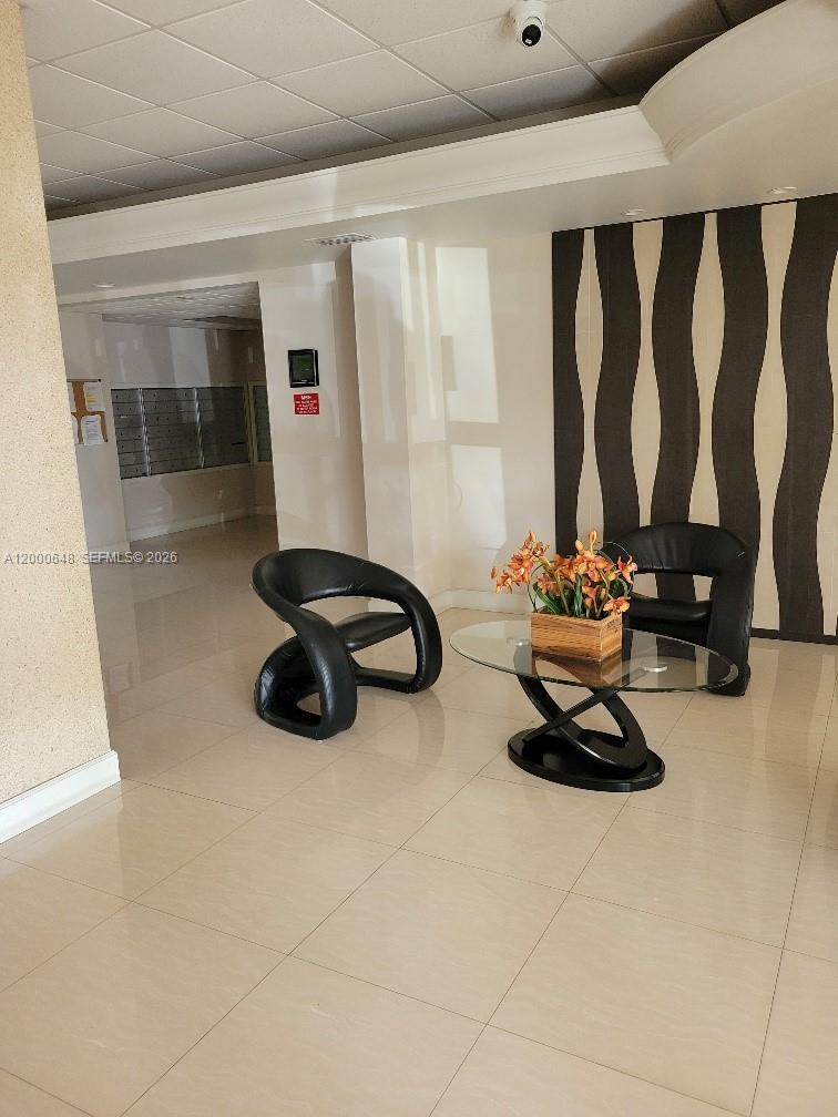 A modern lobby features two black chairs, a glass coffee table, and a decorative wall — 1833 S Ocean Dr # 307, Hallandale Beach FL 33009, HALLANDALE BEACH, FL