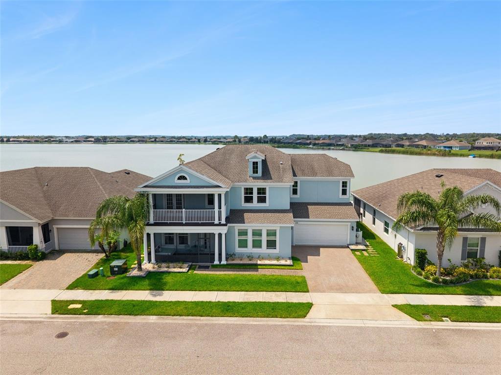 An aerial view of a two-story light blue house with a lake in the background — 359 BLUE CYPRESS DRIVE, GROVELAND, FL